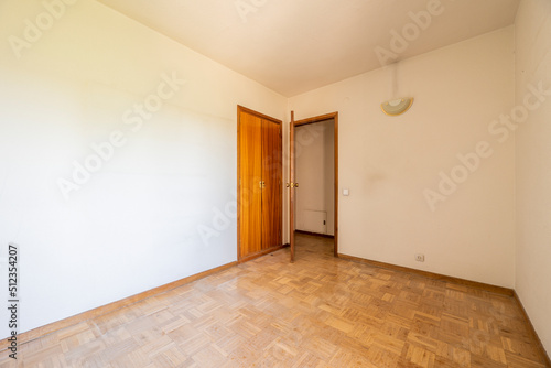 Empty room with oak parquet flooring and woodwork on doors and cabinets