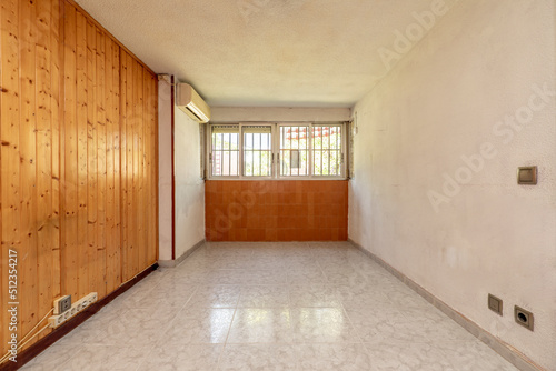 Empty room with aluminum windows and air conditioning with ceramic floors and a wall with brown tiles