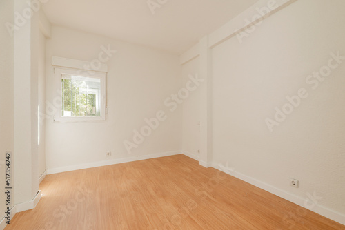 Empty room with oak parquet floor, white painted walls and aluminum windows overlooking a park © Toyakisfoto.photos