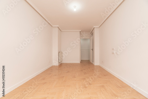 Empty room with wood-like stoneware floors, white painted walls and aluminum radiator