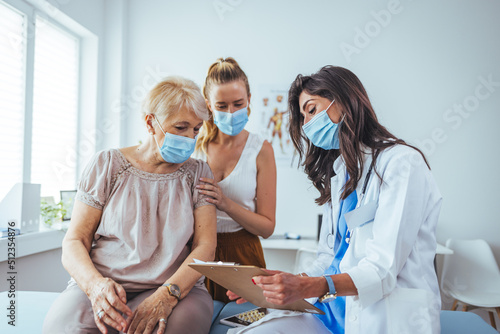 Senior woman and adult daughter with female doctor. Professional smiling doctor meeting a senior patient and her daughter at the hospital, medical service concept photo