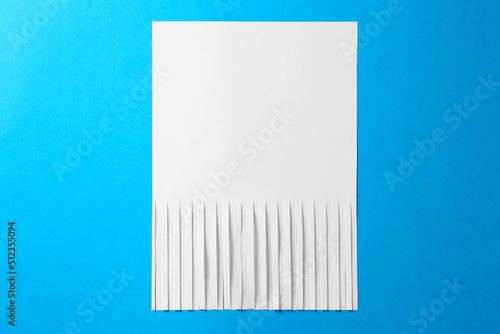 Half shredded sheet of paper on light blue background, top view