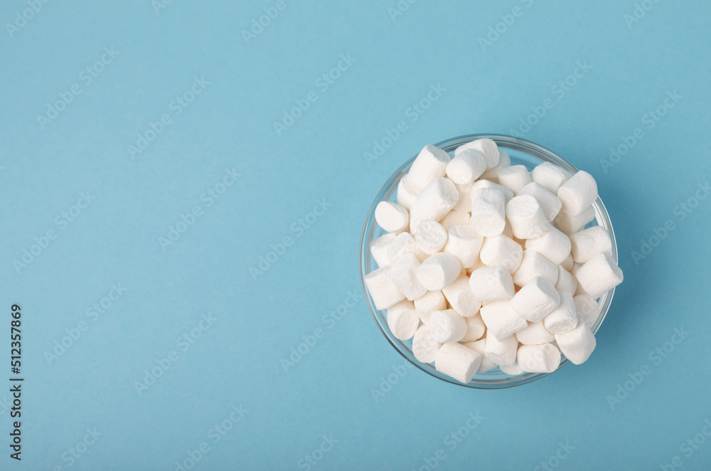 Marshmallows in bowls on a blue background.Closeup gummies.Snacks and snacks for parties.Spice for coffee and cocoa.Winter food concept.Place for text.Space for copy. Marshmallows in bowls on a blue background.Closeup gummies.Snacks and snacks for parties.Spice for coffee and cocoa.Winter food concept.Place for text.Space for copy.