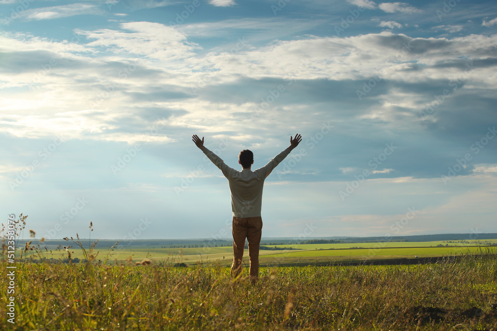 Young man with raised hands in the green meadow. Photo was taken 17 June 2022 year, MSK time in Russia. Young man with raised hands in the green meadow. Photo was taken 17 June 2022 year, MSK time in Russia.