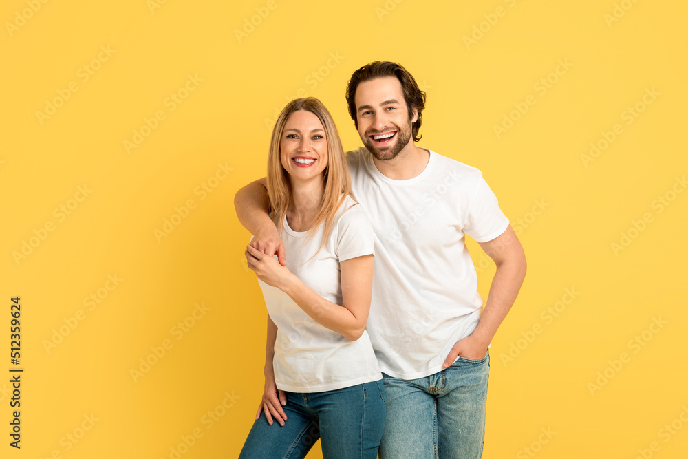 Cheerful glad millennial caucasian male hugging blonde lady in white t-shirts, looking at camera Cheerful glad millennial caucasian male hugging blonde lady in white t-shirts, looking at camera
