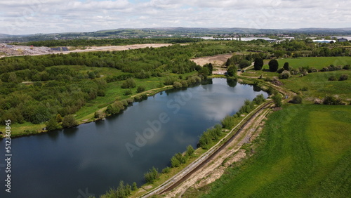 Aerial view looking down onto a lake surrounded by trees and countryside. 