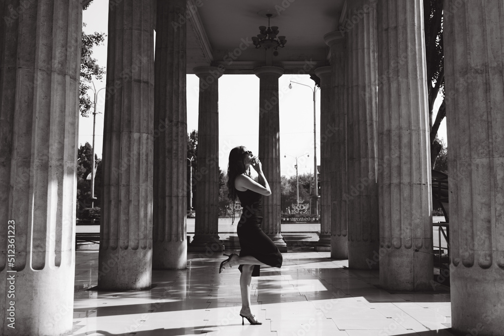 A beautiful girl with a hairstyle in a black dress on the street with a cigarette in her hands smokes, black and white photo. A beautiful girl with a hairstyle in a black dress on the street with a cigarette in her hands smokes, black and white photo.