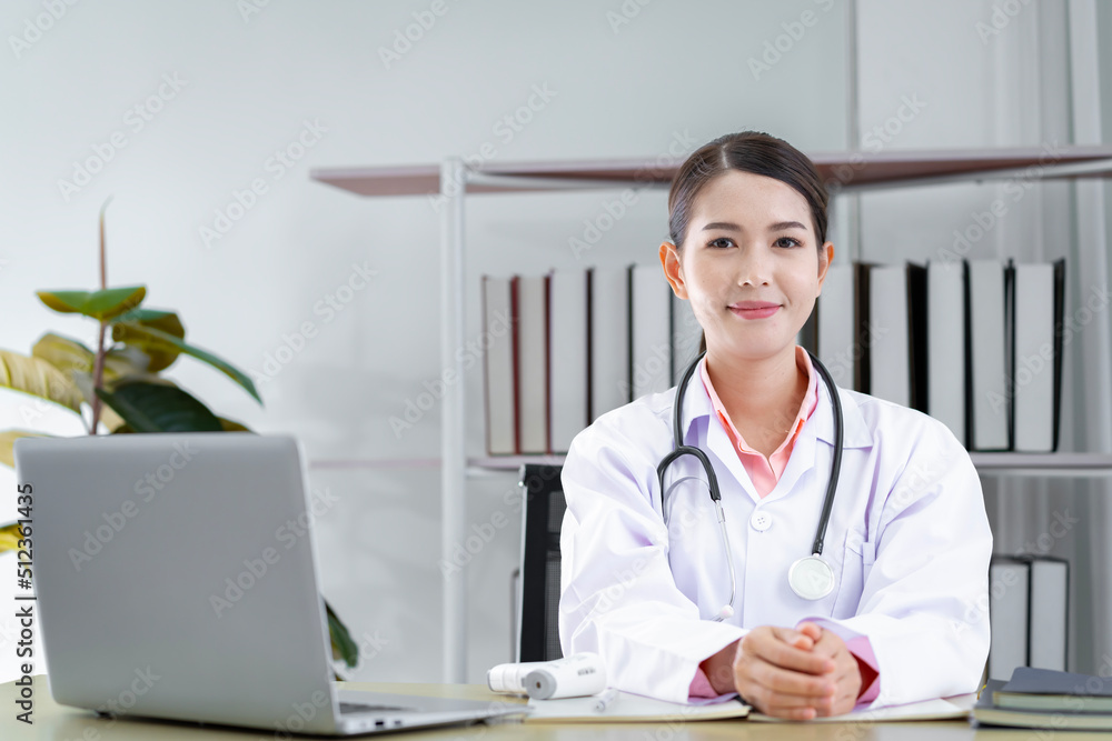 An Asian female doctor in Thailand is communicating with patients over the Internet with her personal laptop at the hospital to advise patients at home. An Asian female doctor in Thailand is communicating with patients over the Internet with her personal laptop at the hospital to advise patients at home.