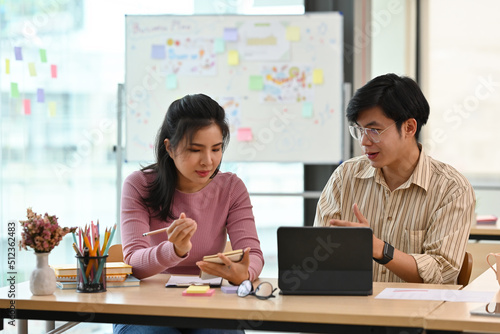 A portrait of Asian businesspeople sitting in an office, working together on a tablet and having a conversation, for business and technology concept.