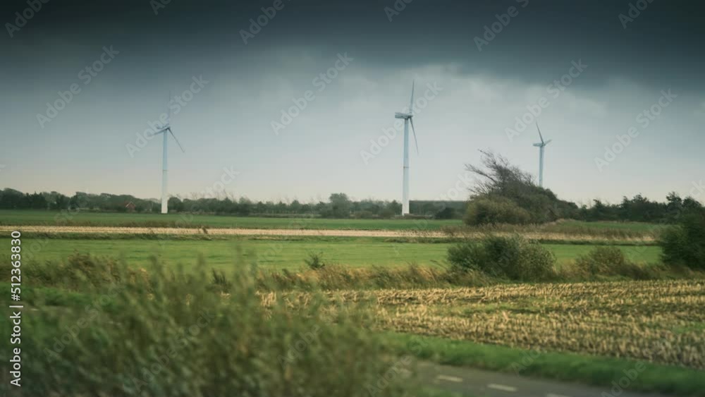 Wind turbines on the green lush field. Dark stormy clouds move fast above. Slow-motion, pan follow. Wind turbines on the green lush field. Dark stormy clouds move fast above. Slow-motion, pan follow.