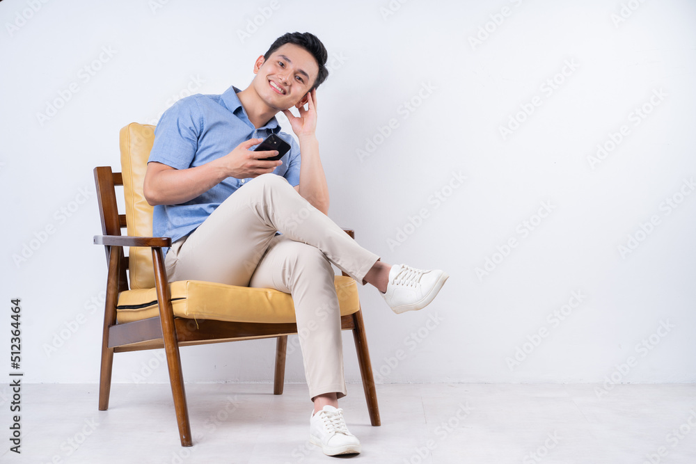 Image of young Asian man sitting on chair Image of young Asian man sitting on chair