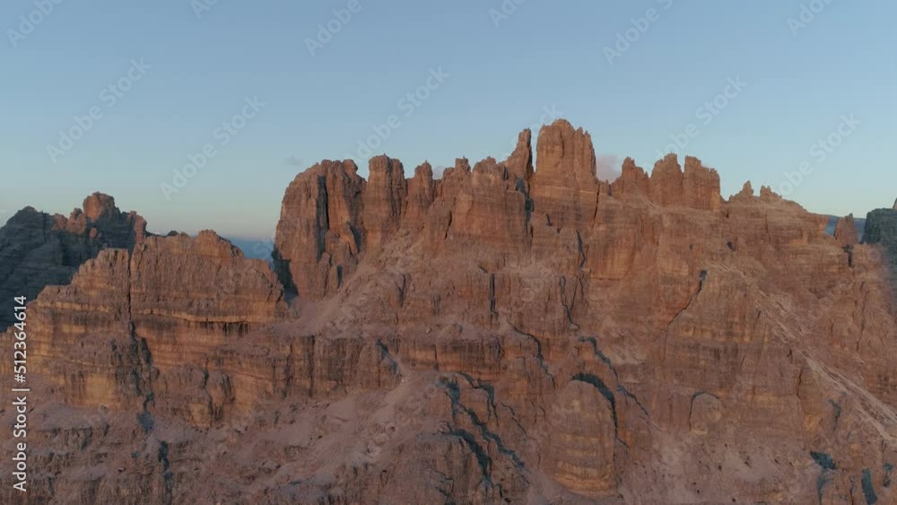 Descending aerial view Tre Cime South Tyrol red sunlit rock formation mountain range peaks Descending aerial view Tre Cime South Tyrol red sunlit rock formation mountain range peaks