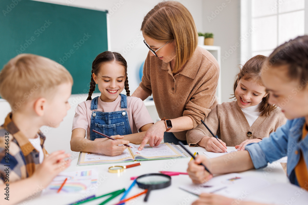 Teacher helping children with schoolwork Teacher helping children with schoolwork