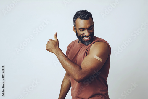 Fototapete mid adult smiling bearded vaccinated man in the studio looking down at plaster w