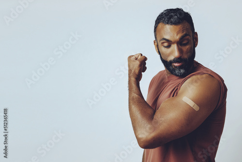 Canvastavla portrait mid adult bearded vaccinated man in the studio flexing arm muscle with