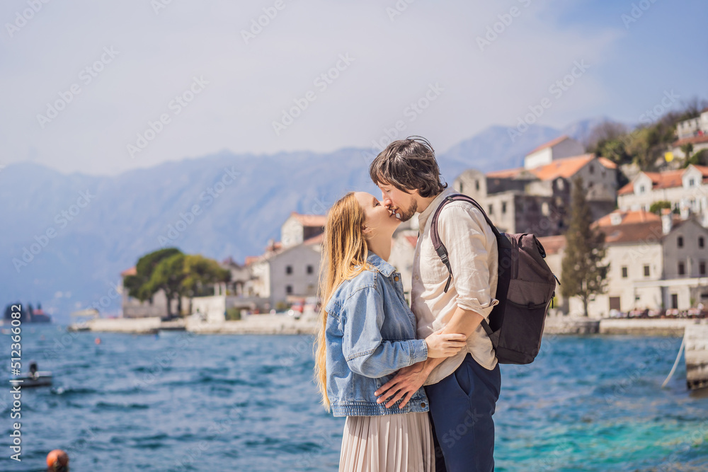Happy couple in love man and woman tourists enjoying Colorful street in Old town of Perast on a sunny day, Montenegro. Travel to Montenegro concept. Scenic panorama view of the historic town of Perast