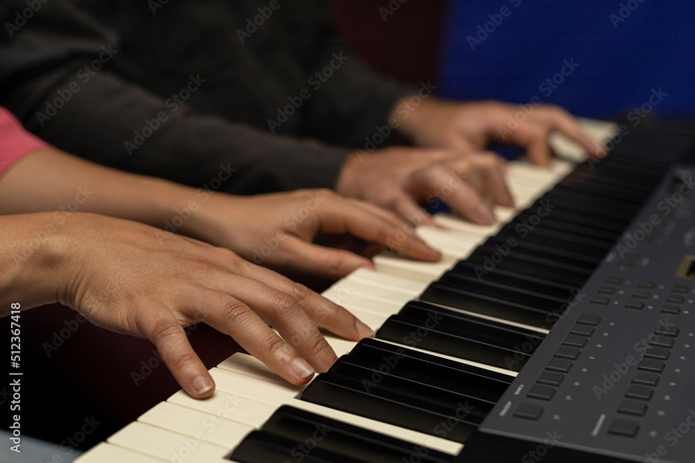 Latin American teacher plays the piano keyboard with her student with four hands. Concept of music lessons