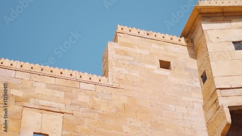 Closeup shot of carved and decorated walls of the Jaisalmer Fort at Rajasthan in India. Carved walls in front of the clear blue sky. Walls made out of sandstone. Ancient architecture of India.  photo