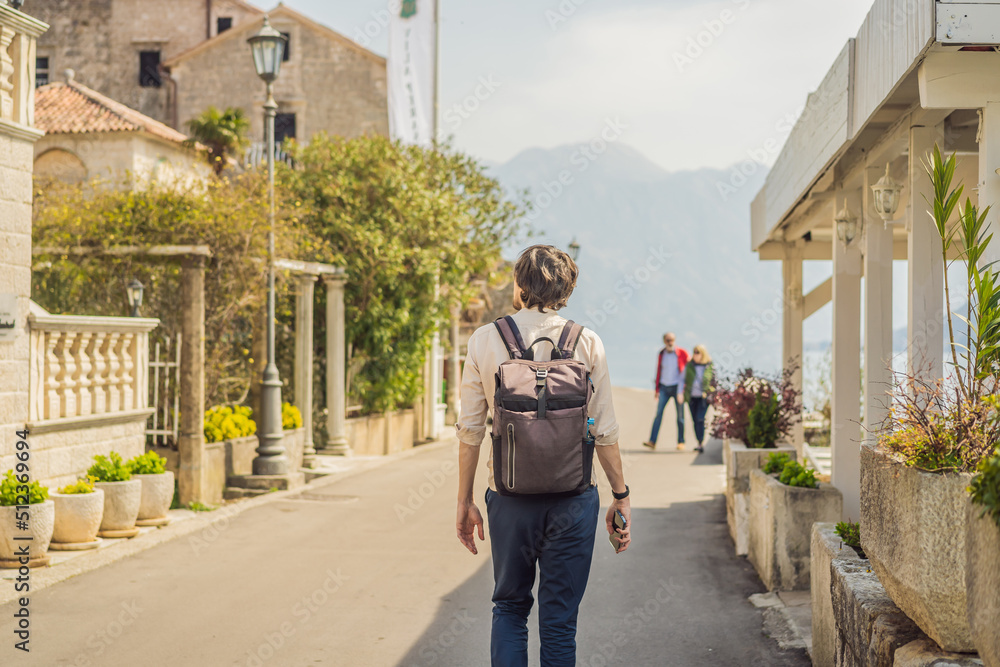 Man tourist enjoying Colorful street in Old town of Perast on a sunny day, Montenegro. Travel to Montenegro concept. Scenic panorama view of the historic town of Perast at famous Bay of Kotor on a