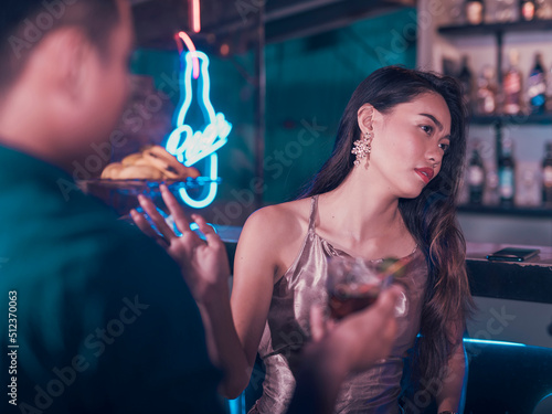 A young woman rebuffs a man trying to hookup with her. Uninterested in meeting new men or turned off at her date. Nightclub or bar scene. photo