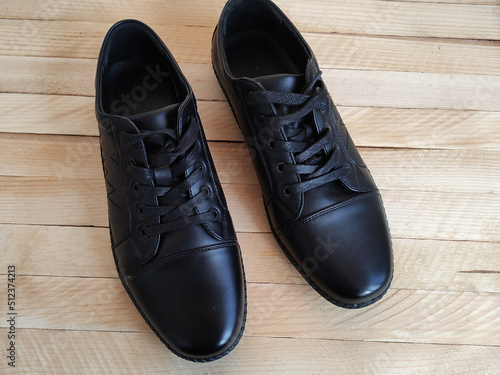 Black leather sports shoes on wooden background