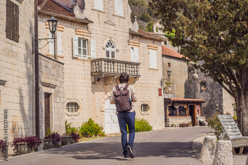 Man tourist enjoying Colorful street in Old town of Perast on a sunny day, Montenegro. Travel to Montenegro concept. Scenic panorama view of the historic town of Perast at famous Bay of Kotor on a © galitskaya