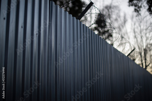 Steel fence in woods. Fence of industrial zone.