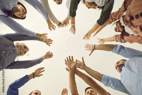 Team of business people reaching up together. Group of young and mature people joining hands, white background, cropped low angle shot, from below bottom view close up. Teamwork, participation concept