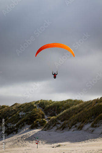 paraglider in the sky over dunes