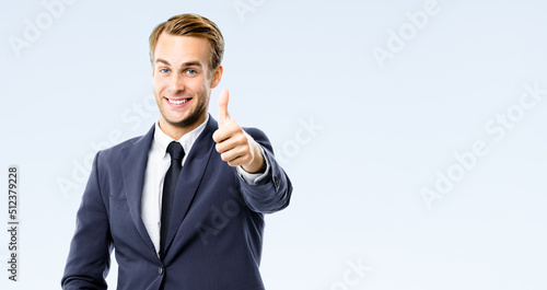 Photographie Happy businessman in black suit, white shirt, necktie show thumb finger up, like, agree hand gesture, isolated on grey background