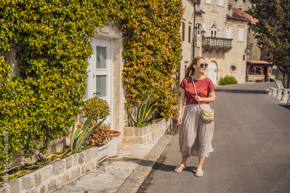 Woman tourist enjoying Colorful street in Old town of Perast on a sunny day, Montenegro. Travel to Montenegro concept. Scenic panorama view of the historic town of Perast at famous Bay of Kotor on a Woman tourist enjoying Colorful street in Old town of Perast on a sunny day, Montenegro. Travel to Montenegro concept. Scenic panorama view of the historic town of Perast at famous Bay of Kotor on a