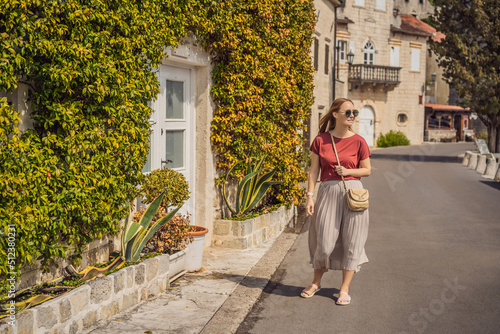 Woman tourist enjoying Colorful street in Old town of Perast on a sunny day, Montenegro. Travel to Montenegro concept. Scenic panorama view of the historic town of Perast at famous Bay of Kotor on a