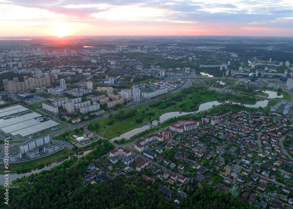 Obraz premium River in city on sunset, aerial view. Suburb houses and multi-storey residential buildings near river in Minsk, Belarus. Cottages and wooden suburb house. Suburban house on sunset panarama, drone view