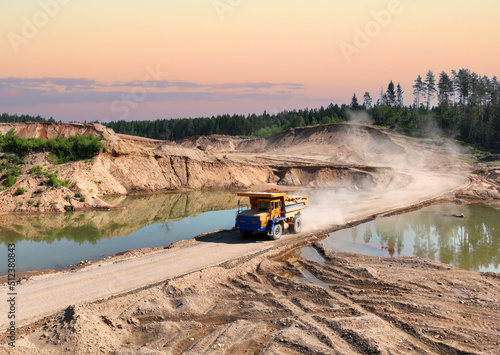Mining excavator loads sand into dump truck. Excavator loads sand rock into a haul truck. Sand pit development. Mining industry. Electric rope shovel dropping rock ore. Sand mining in opencast. photo