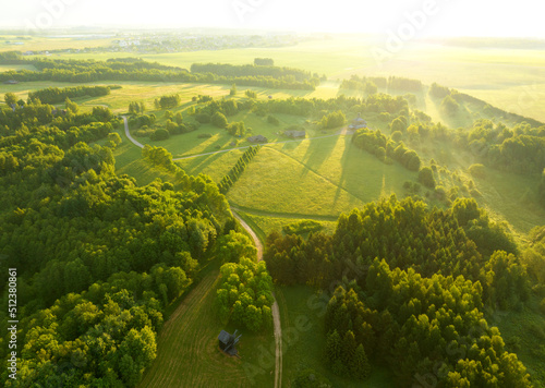 Village with wooden houses near forest. Field and forest in wild on sunrise. Country house in rural. Green fields and farmland. Village aerial view. Suburban house in rural. Old rural house in village
