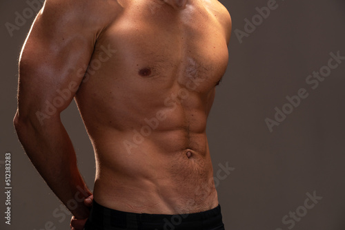 Strong athletic man. Close up view of the fitness model showing his perfect abs isolated on black background with copy space