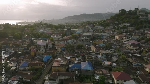 Fast aerial flyover of downtown Freetown, Sierra Leone during the sunrise with morning traffic.