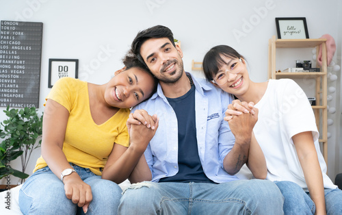 Handsome man resting on bed in home hugging two attractive females, ladies polyamory concept.Diversity gender Equality Love of Trio people.Polyamorius family lover ,Complicated relationship. photo