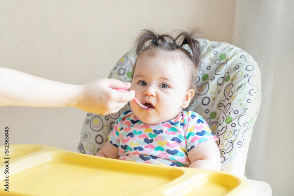 baby eats mashed potatoes, mom feeds baby from a spoon, baby food concept baby eats mashed potatoes, mom feeds baby from a spoon, baby food concept