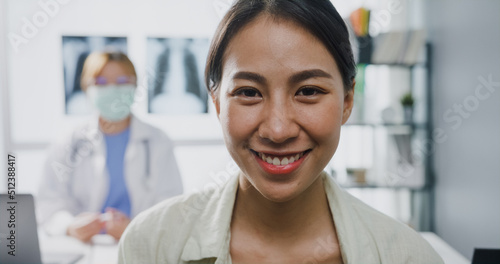 Confident Asia lady doctor and young patient girl gesturing thumbs up  smile and looking at camera while medical consultation at desk in health clinic or hospital. Consult and therapy concept.