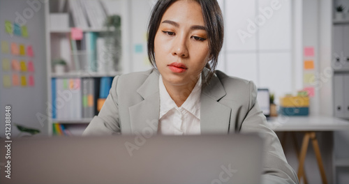 Young Asian businesswoman sit on desk with laptop overworked tired burnout syndrome at office. Exhausted lady with sleeply eye at workplace, Girl not enjoy unhappy with work, Work mental health. photo