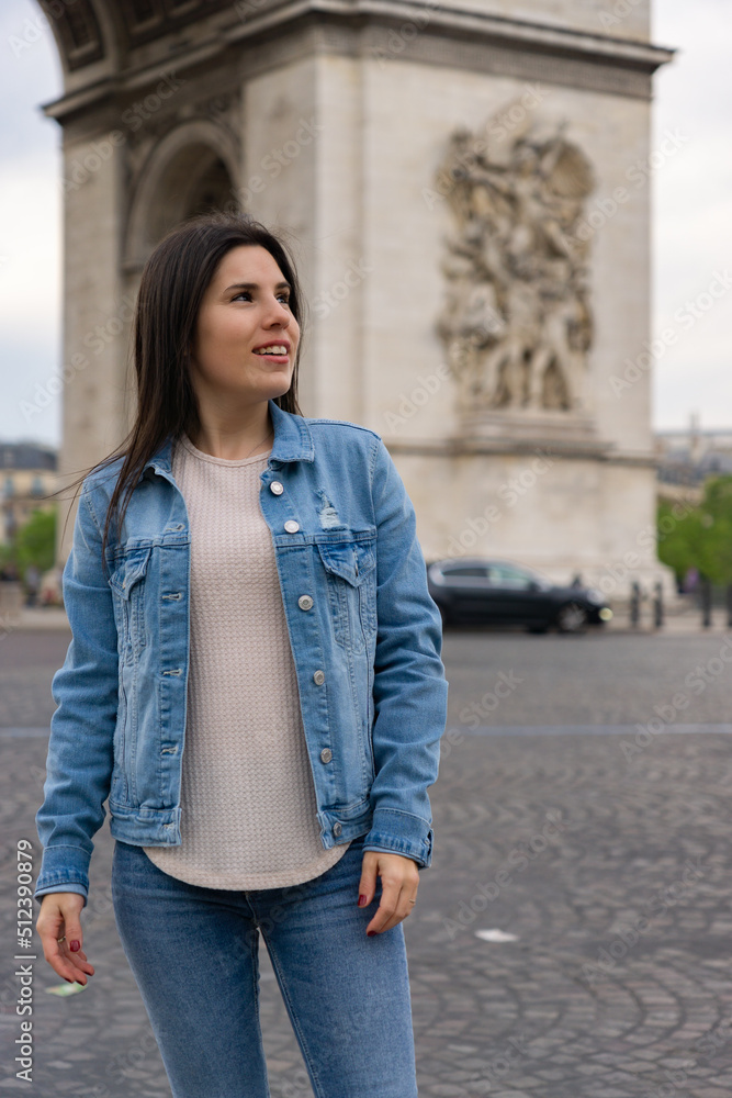 Close-up of a young woman tourist smiling and happy while posing and behind the Triumphal Arch in paris. Close-up of a young woman tourist smiling and happy while posing and behind the Triumphal Arch in paris.