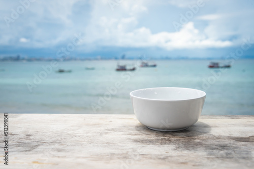 white cup put on the wooden floor, on the sea background, healthy drinking water.