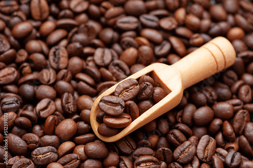 Coffee beans on a wooden  scoop against the background of roasted coffee beans