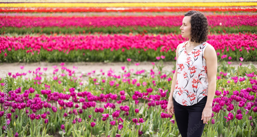 Caucasian Adult Woman looking at fresh Tulip Flowers in a field. Spring Season. Caucasian Adult Woman looking at fresh Tulip Flowers in a field. Spring Season.