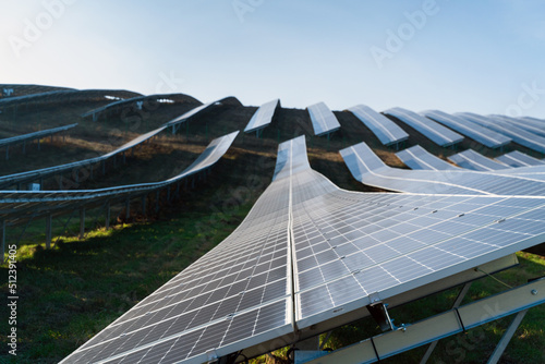 Cropped view of the solar panes in a solar park used for clean energy production. Solar panel on a red roof reflecting the sun and the cloudy blue sky in background