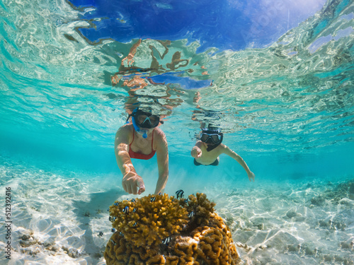 Mother and son discover small fish while snorkeling in Maldives. photo