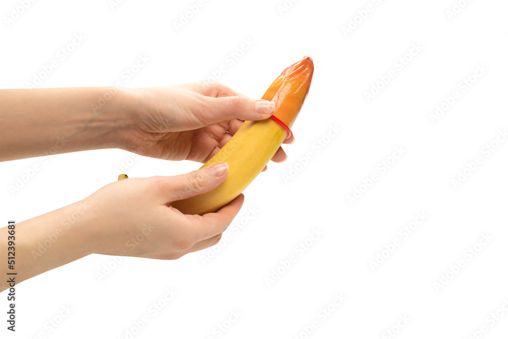Woman put on a condom on a banana. Isolated on white background. Woman put on a condom on a banana. Isolated on white background.