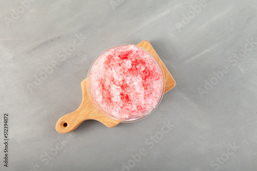 Fruit shaved ice in disposable plastic cup, top view. Slushie - drink. Grey background, selective focus. Refreshing summer drink. Spanish granizado photo