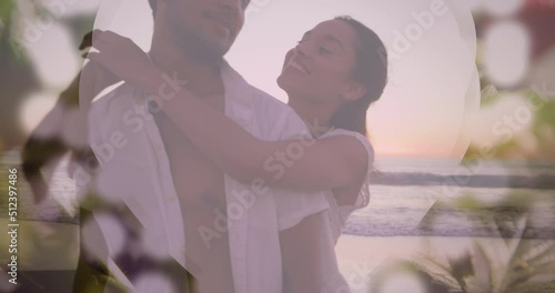 Animation of bokeh over happy biracial couple hugging and kissing on beach
